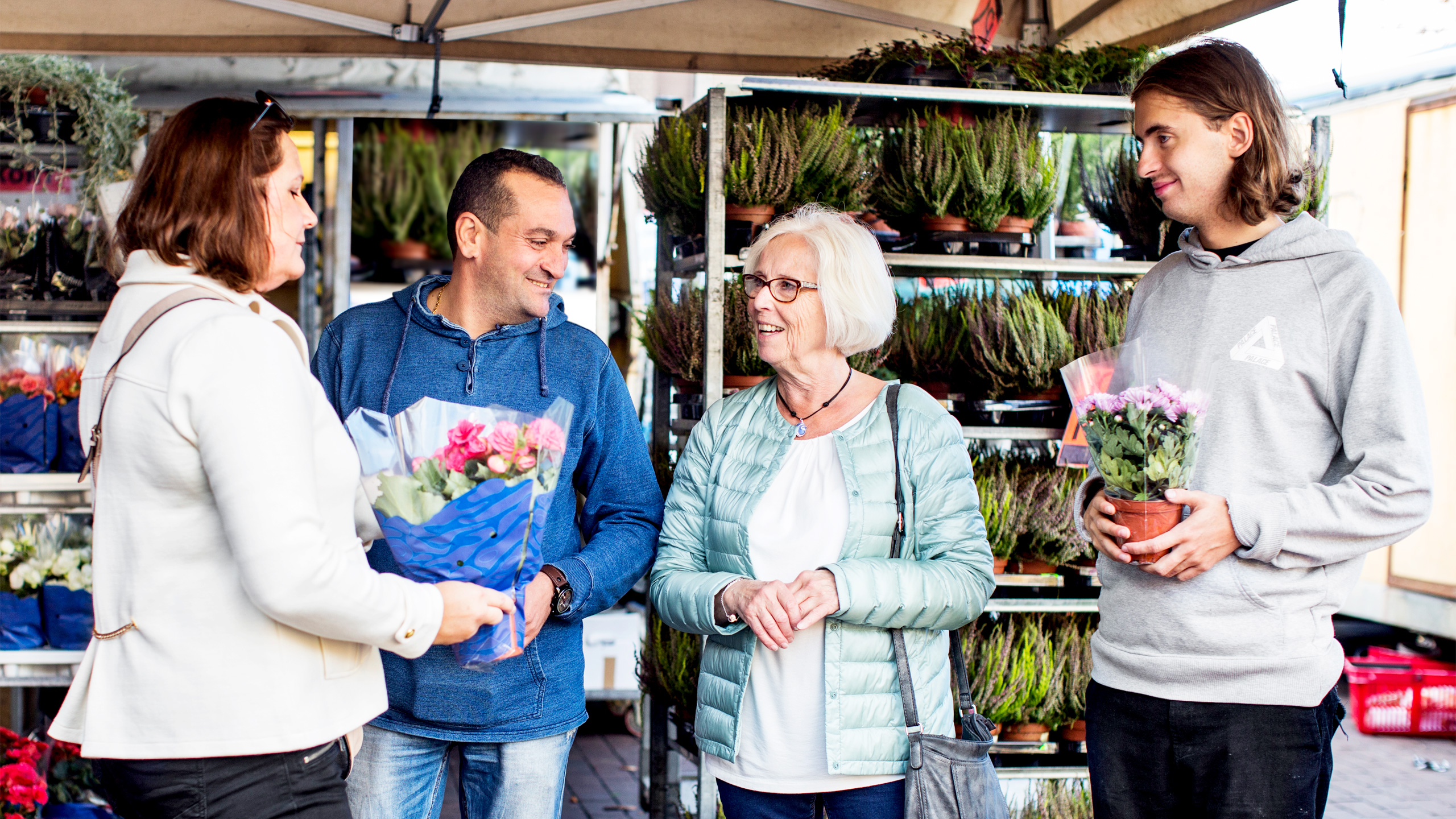 Två kvinnor och två män i olika åldrar hos en torgförsäljare i Skärholmen
